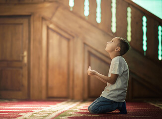 Ramadan Kareem,The Muslim prays in the mosque, the little boy prays to God,Peace and love in the holy month of Ramadan,lifestyle concept