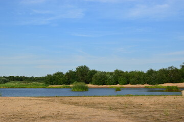 Summer sunny, cloudless day on a sandy beach on the river bank in the forest.