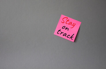 Stay on track symbol. Concept words words Stay on track on pink steaky note. Beautiful grey background. Business and Stay on track concept. Copy space.