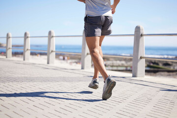 Fitness, sports and legs of man running by ocean for wellness, performance and athlete endurance....