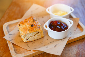 scones and jam on wooden plate, served scones and cream for dessert and tea - fresh homemade butter...