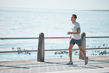 Sports, fitness and man running by ocean in action for wellness, performance and athlete endurance....