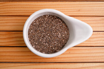Chia seeds in a white bowl on a wooden table. Super food concept. top view