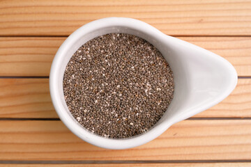 Chia seeds in a white bowl on a wooden table. Superfood concept. top view