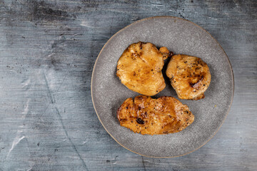 Chicken breasts barbecued and served on the blue plate above dark moody background