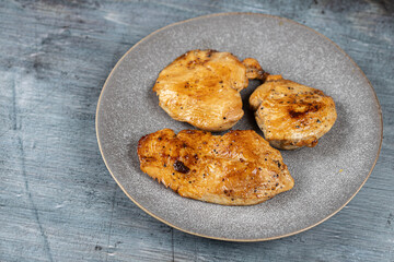 Chicken breasts barbecued and served on the blue plate above dark moody background