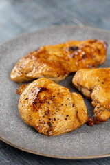Chicken breasts barbecued and served on the blue plate above dark moody background