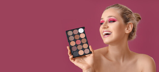 Happy young woman with palette of beautiful eyeshadows on pink background with space for text