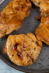 Chicken breasts barbecued and served on the blue plate above dark moody background