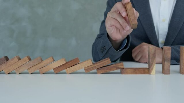 insurance with hands protect domino. Businessman hands stop dominoes falling in business crisis. business risk control and planning and strategies to run prevent insurance businesses.
