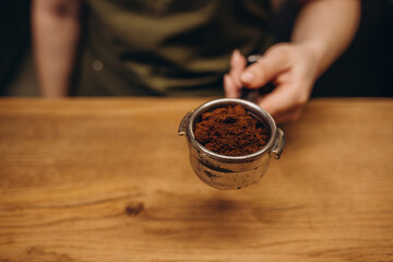 barista tempering ground coffee into espresso pitcher.
