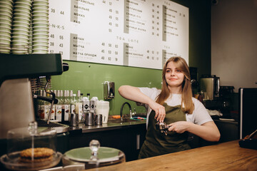 Fototapeta na wymiar Hand of a barista holding a portafilter and a coffee tamper making an espresso coffee.