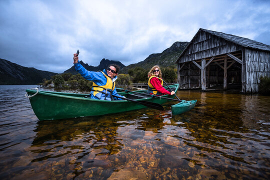 Two females canoeing around the famous boat shed on Dove Lake at Cradle Mountain.
