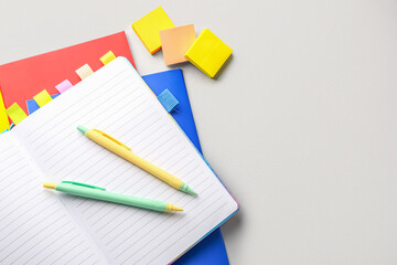 Notebooks, pens and sticky notes on light background, closeup