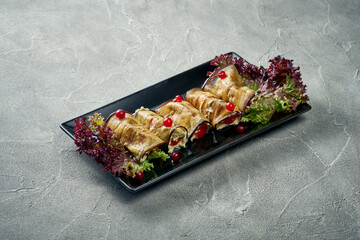 Eggplant rolls with sour cream, garlic and tomatoes in a plate. Concrete background