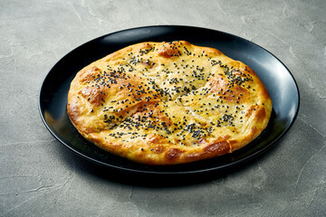 Khachapuri with salty melted cheese in a plate. Concrete background