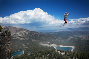 Male highliner in cowboy hat walks a 125 foot highline over a lake in a gap on top of Mammoth Crest