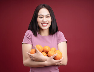 Young Asian woman holding orange fruit on background