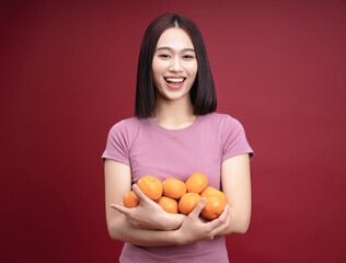 Young Asian woman holding orange fruit on background