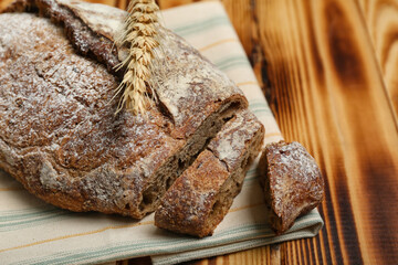 Sliced loaf of rye bread and wheat ear on wooden background