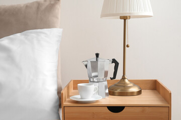 Geyser coffee maker and cup of espresso on nightstand near bed