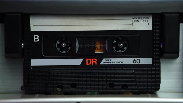 B Side of Audio Cassette Tape Rolling in Deck Player, Close Up
