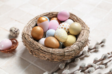 Nest with Easter eggs and willow branches on light tile