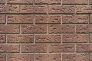 Close view of chocolate brown brick veneer wall with grey mortar joints