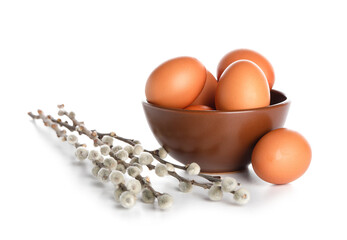 Bowl of Easter eggs and willow branches on white background © Pixel-Shot