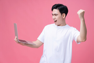 Young Asian man holding laptop on background