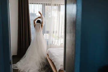 Selective focus. Portrait of a beautiful stylish bride with an elegant dress view from the back near windows. Wedding, people, fashion and beauty concept - bride in a wedding dress. Back view.