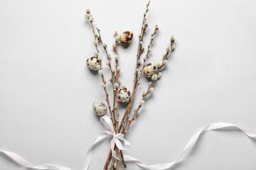 Willow branches tied with ribbon and Easter eggs on light background