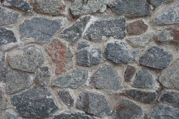 Texture of wall made of grey natural shape fieldstones