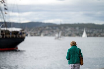 Fototapeta na wymiar people taking photos with their phone of tall ships at a festival in tasmania australia. wooden boat festival. exciting event.
