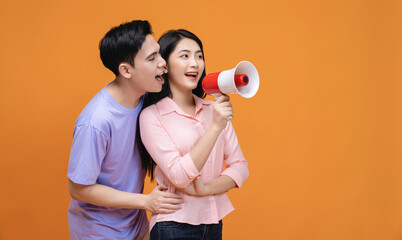 Young Asian couple with megaphone on background