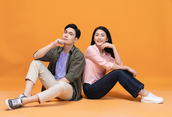 Young Asian couple sitting on background