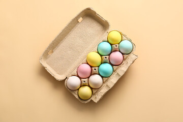 Cardboard holder with painted Easter eggs on color background