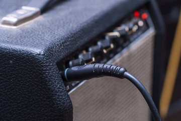Plug jack with cable plugged into a black guitar combo amplifier