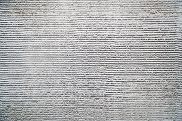 Gray decorative plaster on the wall with pressed horizontal stripes. Plaster background