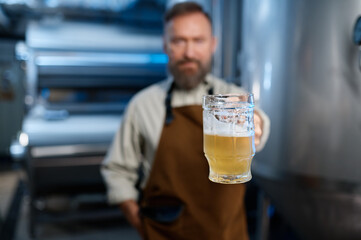 Freshly made craft beer in brewery worker hand, selective focus