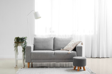 Interior of living room with grey couch, pouf and lamp