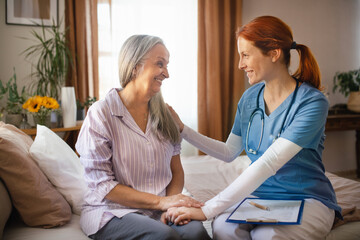 Portrait of nurse holding hand to senior client.