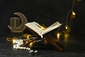 Rehal with Koran, tasbih and glowing lights for Ramadan on dark background
