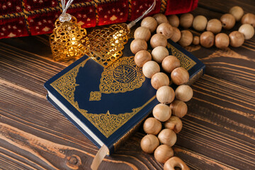 Koran with prayer beads for Ramadan on wooden table, closeup