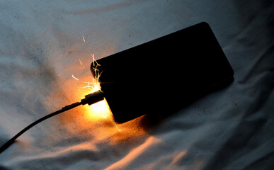 Cell phone battery failure. A smartphone can quickly catch fire set fire, night house, apartment,...