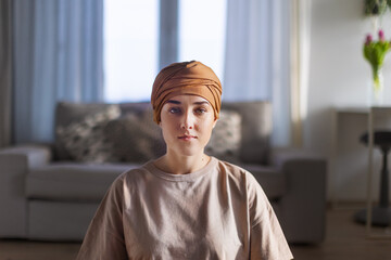 Portrait of young woman with cancer sitting in her apartment.