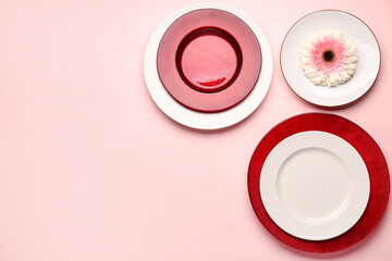 Set of plates and chrysanthemum flower on pink background
