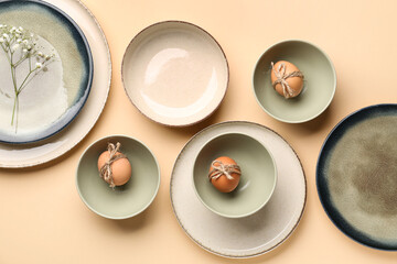 Obraz na płótnie Canvas Set of crockery with Easter eggs and gypsophila flowers on beige background