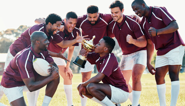 Sports, winner and rugby team with trophy from winning competition, match and sport game. Success, training and happy, excited and players cheer celebrate victory, achievement and kiss award on field