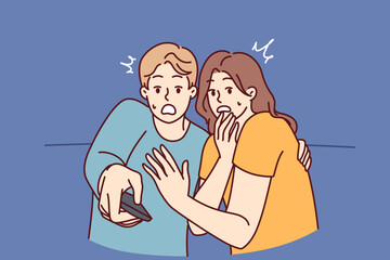 Frightened man and woman with TV remote control are shocked after watching scary movie with murders or monsters. Shocked couple gets scared while watching news on TV because of depressing forecasts 